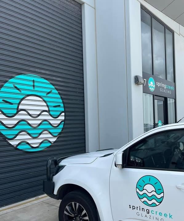 The Spring Creek Glazing unit with the teal logo painted on the roller door and the branded white ute parked outside